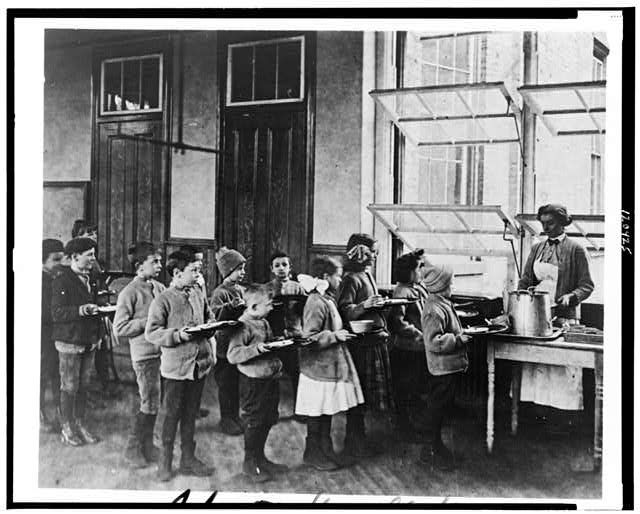 Students in a food line at a Manhattan public school between 1900 and 1920 before lunch.